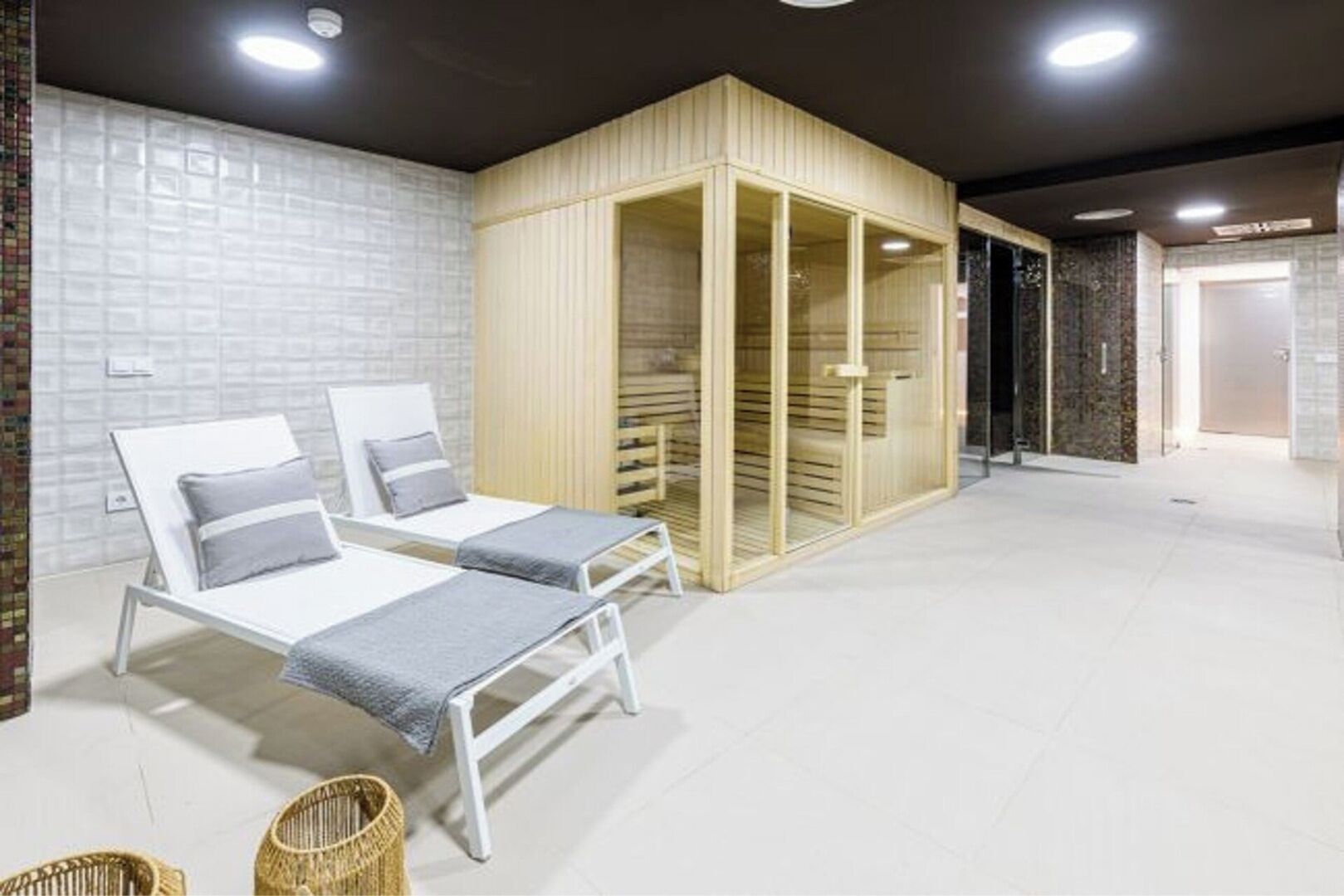 Een spa-ruimte met twee witte bedden, een houten kast en een betegelde vloer.