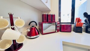 Ett modernt kök med en röd vattenkokare, en brödrost och en kaffebryggare.