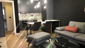 A modern living room with a grey sofa, a coffee table, and a dining area with a table and chairs. - Tirent Apartment Komuna Parisit 1 (Tirana)