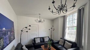 Una sala de estar moderna con un sofá modular, una mesa de centro y un ventanal con cortinas.