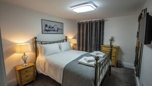 Une chambre à coucher bien rangée, avec un lit, des lampes de chevet, un téléviseur à écran plat et un tableau encadré au mur.