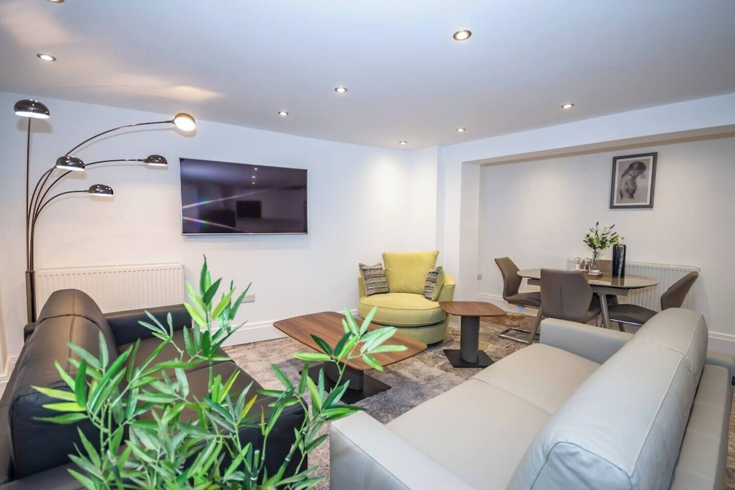 Ein modernes Wohnzimmer mit einer Couch, einem Sessel und einem Esstisch mit Stühlen.