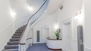 En storslagen trappa som leder upp till en liten plattform med en krukväxt och ett element.