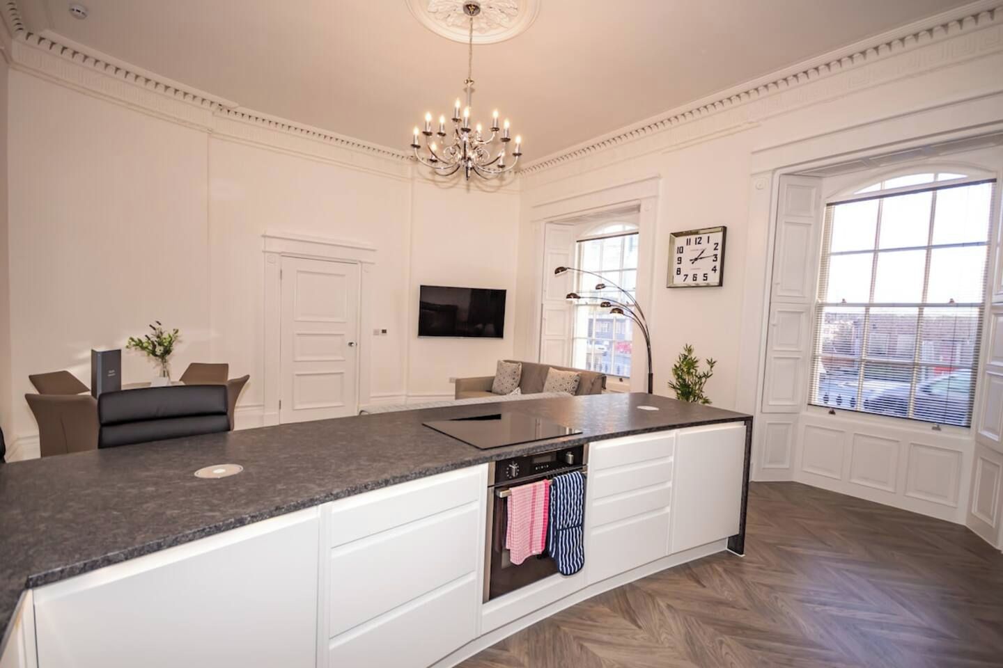 Una cocina amplia con una isla grande, muebles blancos y horno empotrado.