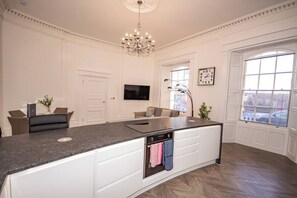 Una cocina amplia con una isla grande, muebles blancos y horno empotrado.