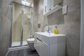 Ein modernes Badezimmer mit einer Duschkabine aus Glas, einem weißen Waschbecken und einer Toilette.