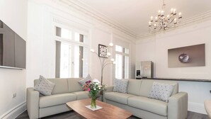 A modern living room with a sectional sofa, a wooden coffee table, and a chandelier.