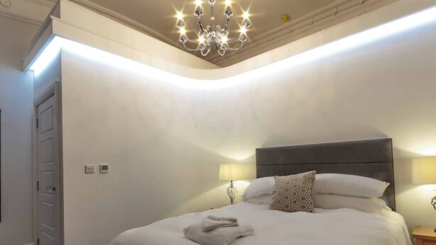 A bedroom with a large bed, a chandelier, and bedside lamps.