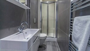 A modern bathroom with a standalone sink, a glass-enclosed shower, and a towel rack.