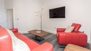 Ein modernes Wohnzimmer mit einem roten Sofa, einem Couchtisch aus Holz und einer Stehlampe.