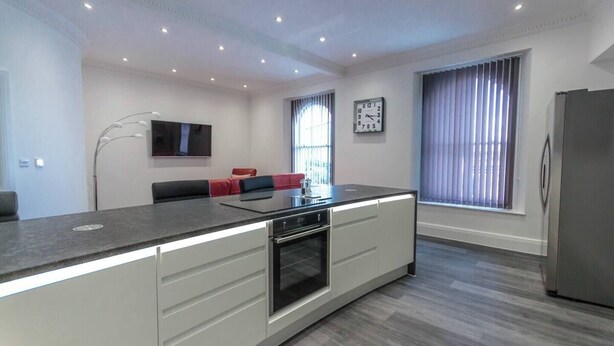 A modern kitchen with a central island, built-in oven, and a refrigerator.