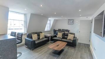 A modern living room with a sectional sofa, a coffee table, and a dining area.