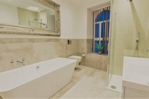 A modern bathroom with a freestanding bathtub, a toilet, and a shower area.