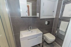 Une salle de bain avec un lavabo blanc, des toilettes et un porte-serviettes.