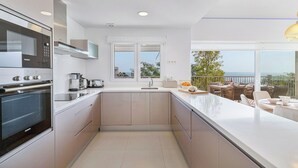 A modern kitchen with a built-in oven and microwave, a large window, and a balcony with outdoor seating. - Stylish apartment with oceanview (Málaga)