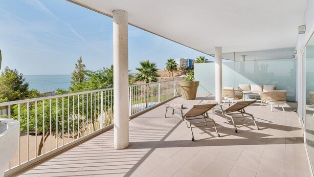 A balcony with sun loungers, a large potted plant, and a view of the sea. - Stylish apartment with oceanview (Málaga)