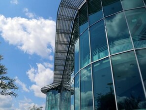 Un bâtiment moderne doté d’une façade en verre incurvé et d’une structure métallique.