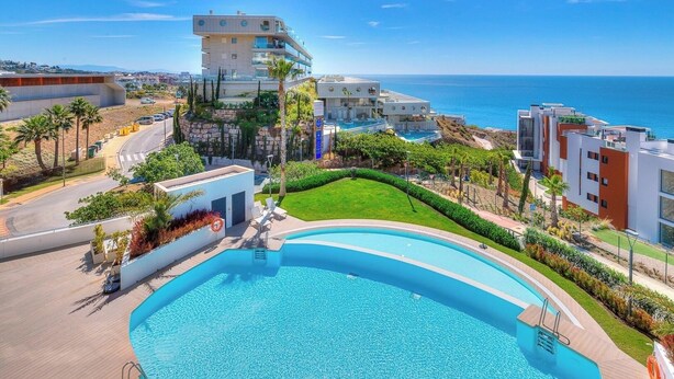 Un hôtel moderne doté d’une grande piscine, offrant une vue sur la mer et comprenant un jardin bien entretenu.