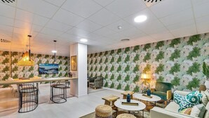 Une chambre d’hôtel moderne dotée d’un coin repas, d’un ensemble de canapés et d’un papier peint à motifs.