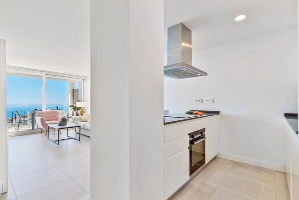 A modern kitchen with a built-in oven and a large window overlooking a balcony.