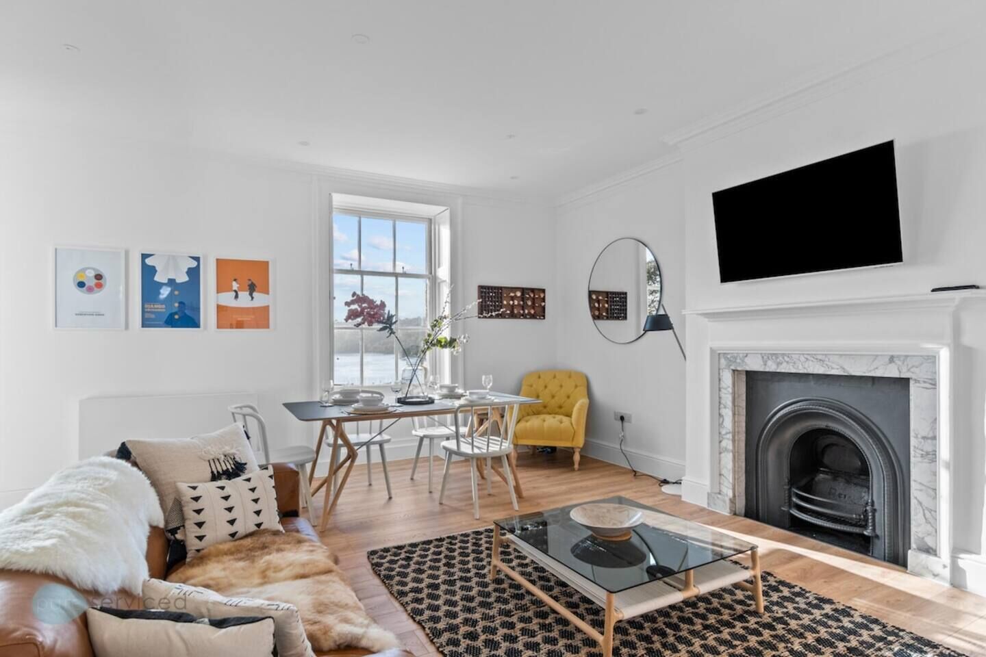 A modern living room with a fireplace, a dining area, and a sofa.