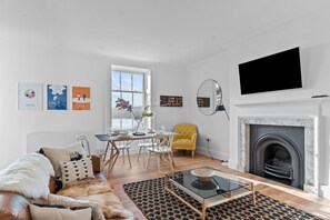 A modern living room with a fireplace, a dining area, and a sofa.