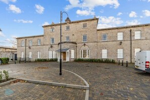 A historic building with a central entrance, multiple windows, and a paved courtyard.