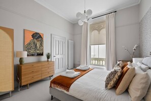 A modern bedroom with a bed, a wooden dresser, a painting, and a radiator.