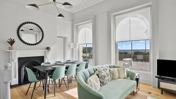 A modern living room with a fireplace, dining area, and large windows offering a view.