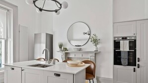 A modern kitchen with a central island, a built-in oven, and a large window. - Hurlingham by Pureserviced (Plymouth)