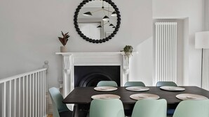 A dining room with a fireplace, a round mirror, and a radiator. - Hurlingham by Pureserviced (Plymouth)