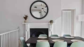 A dining room with a fireplace, a round mirror, and a radiator.