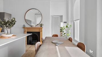 A dining area with a long table, chairs, a fireplace, and a large mirror.
