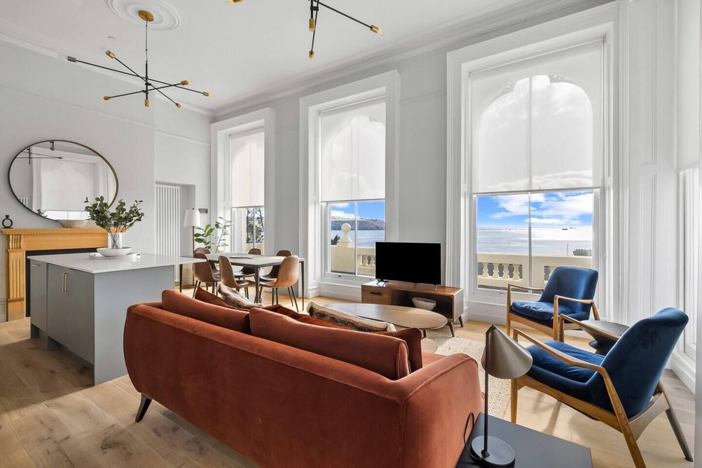 A modern living room with a sofa, chairs, a TV, and a dining area with a table and chairs.