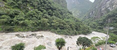 A river with a rocky bed, surrounded by dense green forest and steep cliffs.