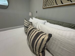 A bedroom with a bed, pillows, a lamp, and a painting on the wall.