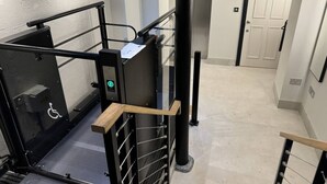 A modern elevator with a handrail and a wheelchair-accessible button. - Martello By Pureserviced (Plymouth)