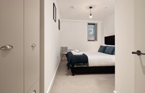 Une chambre à coucher avec un lit, une table de chevet, une chaise et une fenêtre.