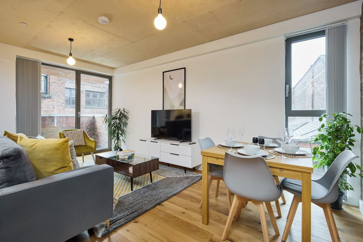 A modern living room with a sofa, coffee table, and dining area with chairs and a table set for two.