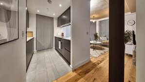 A modern kitchen with dark cabinets, a built-in oven, and a window overlooking the living area.