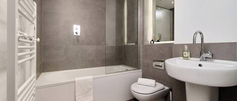 A modern bathroom with a bathtub, toilet, and sink.