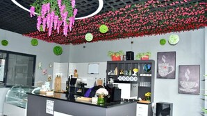 Una moderna zona de recepción con mostrador, máquinas de café y plantas decorativas.