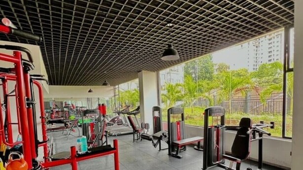 Un gimnasio con equipo de ejercicio variado, una banca roja y mancuernas.