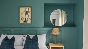 A bedroom with a bed, pillows, a bedside table with a lamp, a mirror, and a framed picture on the wall. - Huge spacious 8 bed luxury villa (Plymouth)