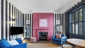A living room with a fireplace, striped walls, and a television. - Huge spacious 8 bed luxury villa (Plymouth)