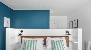 A bedroom with a bed, two bedside lamps, a white headboard, and a blue accent wall. - 2 Bed - Apartment No. 1 Windsor Villas (Plymouth)