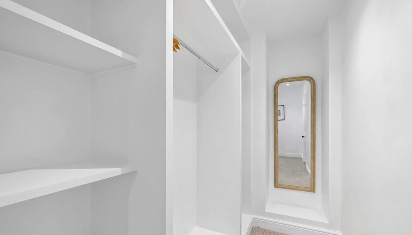Un interior en tonos blancos con un espejo y una puerta.