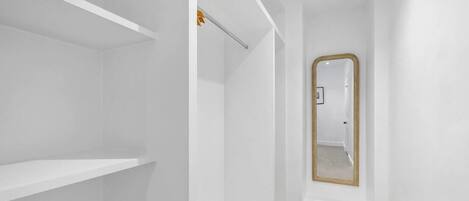 Un interior en tonos blancos con un espejo y una puerta.