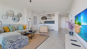 A modern living room with a sofa, coffee table, and a dining area with a chair. - Modern 3bdr aprt - Ocean view (Fuengirola)