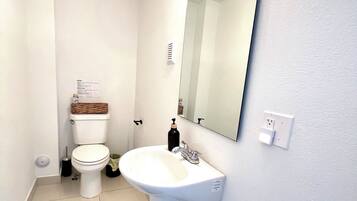 Une salle de bain avec des toilettes, un lavabo et un miroir.
